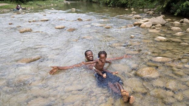 Homem brincando em rio com filho