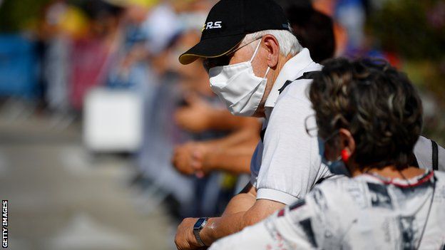 Spectators at a cycling event wearing masks