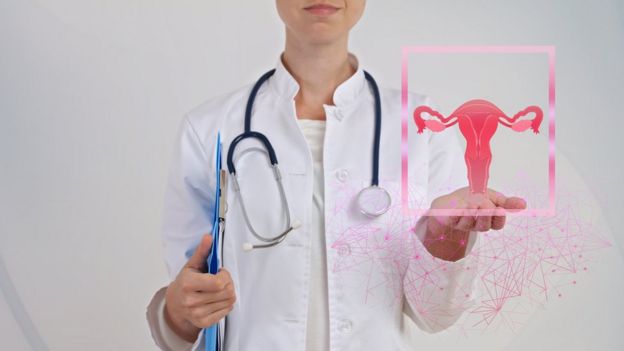 Médica com ilustração de um útero, trombas e ovário