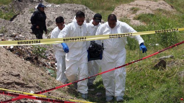 Policías ministeriales llevan un cuerpo de una fosa común en México.