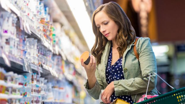 Mujer en un supermercado leyendo la etiqueta de un yogur