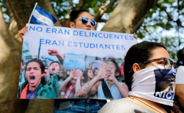 A woman holds a sign reading 'They were not criminals, they were students' in a protest in Nicaragua, July 2018