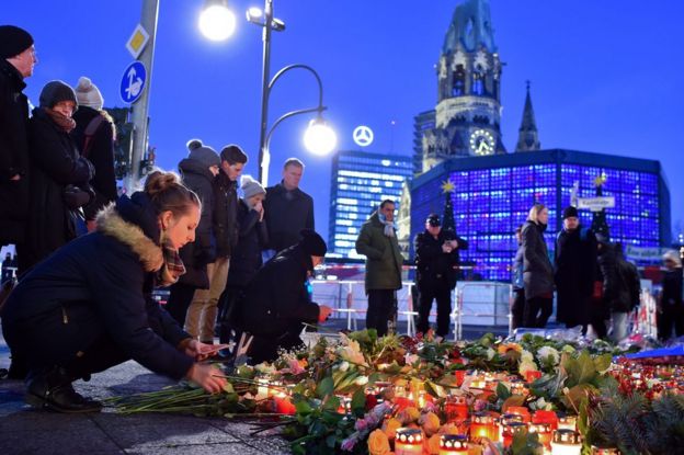 Grupo de gente colocando velas y flores en las calles de Berlín