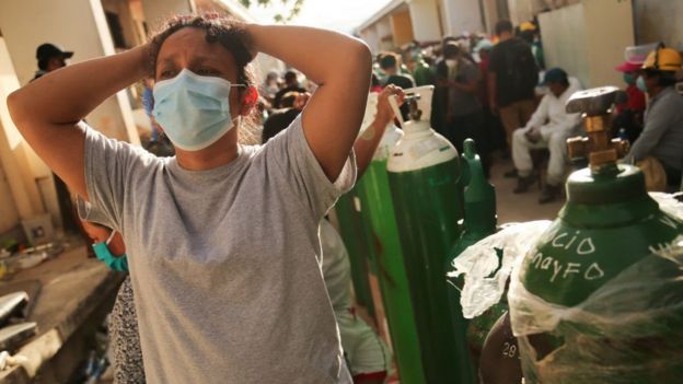 Mujer con las manos sobre la cabeza con gesto de desesperacin haciendo cola para llenar un baln de oxgeno