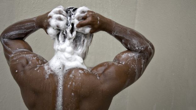 Homem lavando o cabelo com shampoo