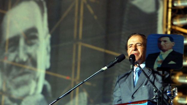 Carlos Menem con dos imágenes de Perón, durante un acto de campaña en 2003