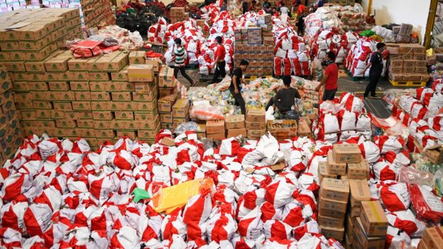 Pekerja mengemas paket bantuan sosial (bansos) di Gudang Food Station Cipinang, Jakarta, Rabu (22/04).