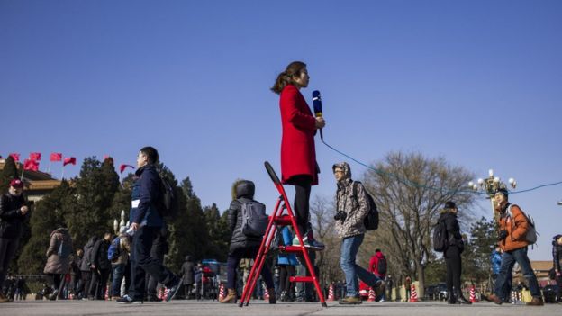 一名女记者在北京人民大会堂前站在梯子上出镜（资料图片）