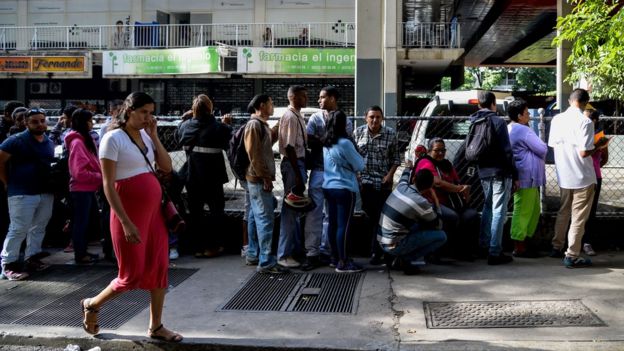 Una fila de gente para comprar bienes básicos.