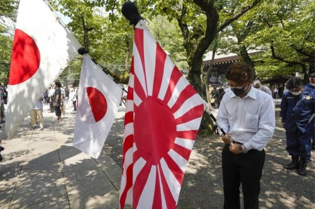 People holding Japan"s national flags and the rising sun flag offer one minute silence for the war dead at Yasukuni Shrine on the 75th anniversary of the end of World War Two, at in Tokyo, Japan, 15 August 2020.