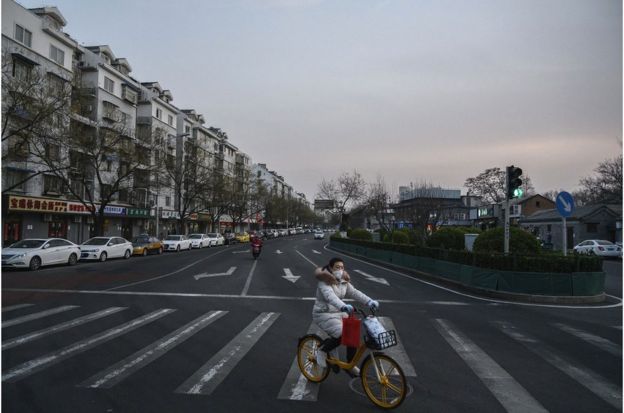 一名北京妇女在街上骑自行车时戴着防护口罩