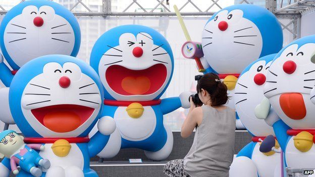 A journalist photographs life-size figures of Doraemon