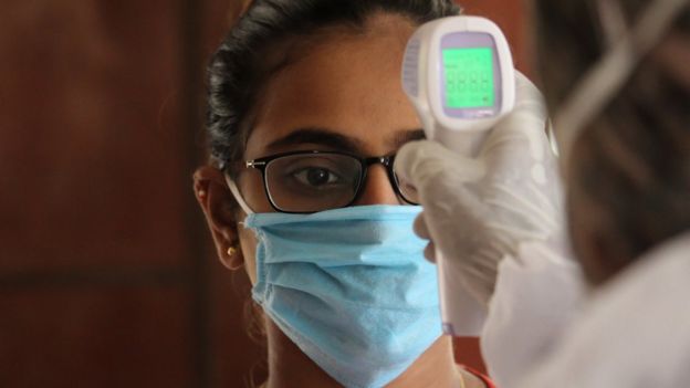 A man using thermal scanner to check temperature of a woman