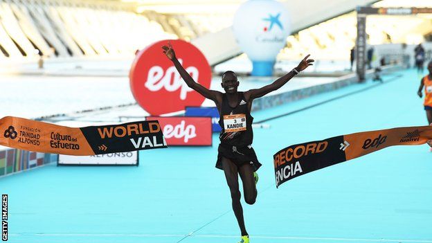 Kibiwott Kandie holding his arms aloft as he crosses the finish line after setting a new world half marathon record