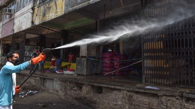 A sanitation worker spraying disinfectant over shops in Azadpur Mandi, on May 1, 2020 in New Delhi, India.