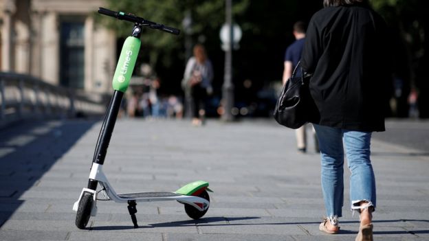 Imagem mostra patinete estacionado sobre calçada em Paris, enquanto pessoas caminham