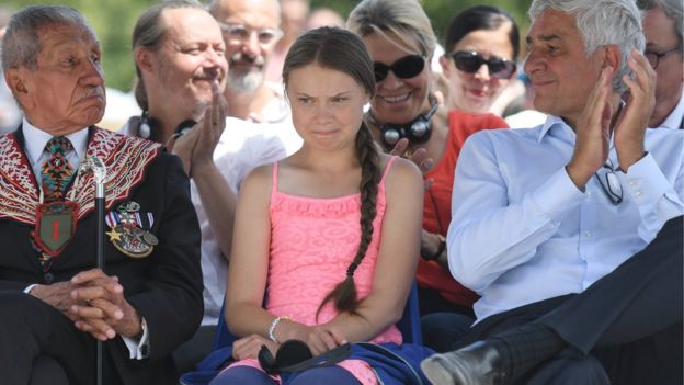 Greta Thunberg sitting in a crowd of people