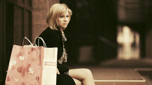 Mulher sentada ao lado de sacolas de compra