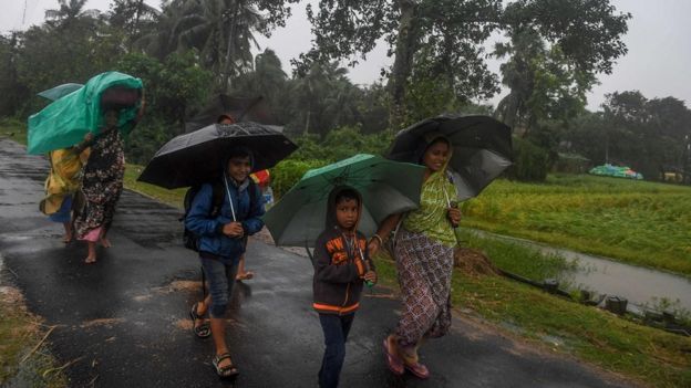 Villagers holding umbrellas carry their belongings on their way to enter a relief centre in India