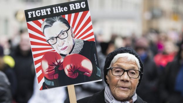 An older marcher holds a sign that says 'Fight like RBG' with a picture of Ruth Bader Ginsberg