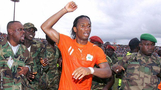 Drogba is escorted from the Bouake pitch by security personnel