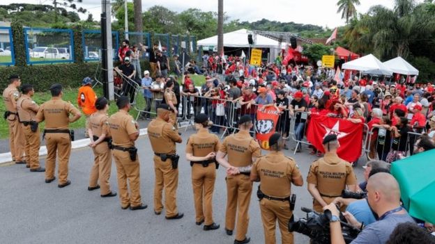 Policiais e cidadãos em frente à sede da Polícia Federal, onde Lula cumpre pena de prisão, em Curitiba