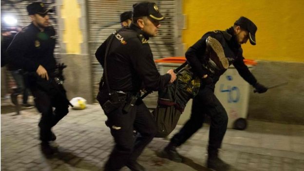 Spanish police run through the streets carrying a protester who fell down during a police charge in the Lavapies district