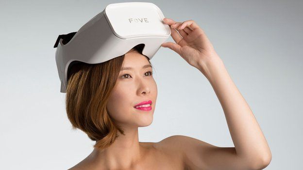 A woman lifting a white virtual reality headset up from her forehead