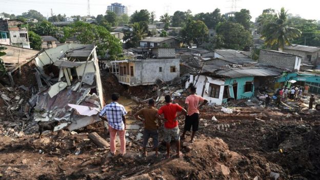 Homens observam cenário de destruição após desmoronamento em Manila