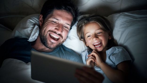 Padre e hija leyendo cuento en tablet