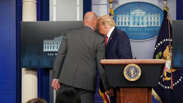 US President Donald Trump talks with a secret service agent before leaving a coronavirus briefing at the White House, August 10, 2020
