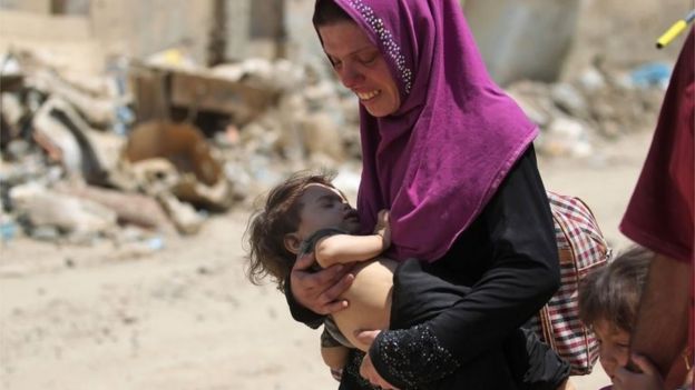 An Iraqi woman carries a child as she flees from the Old City of Mosul on June 20, 2017, during the ongoing offensive by Iraqi forces to retake the last district still held by the Islamic State (IS) group.