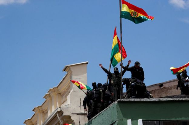 Police officers flying flags on the roof of a police station in La Paz on Saturday