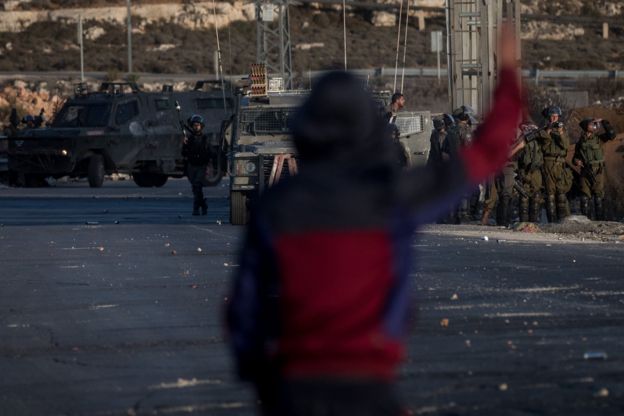 فتى فلسطيني يقف في مواجهة عناصر من الجيش الإسرائيلي