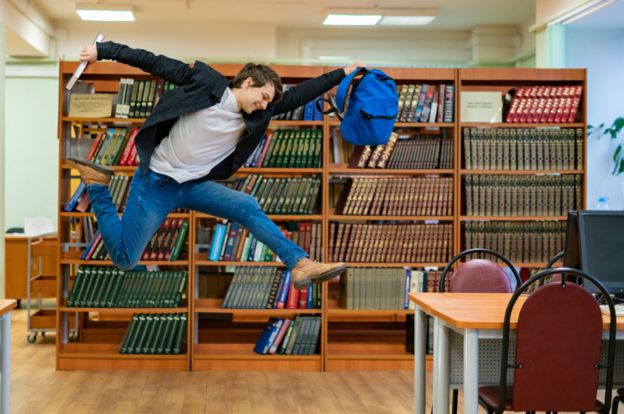 Un joven salta en una biblioteca