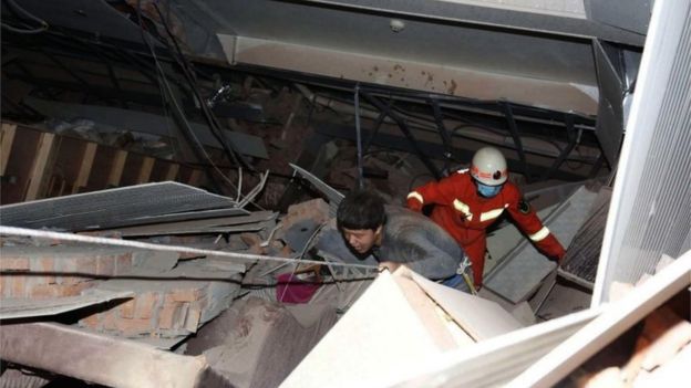 2020年3月7日、中国南東部の福建省の泉州市にある倒壊した5階建てのホテルの瓦の外を歩いて負傷した男性を救助者が追う