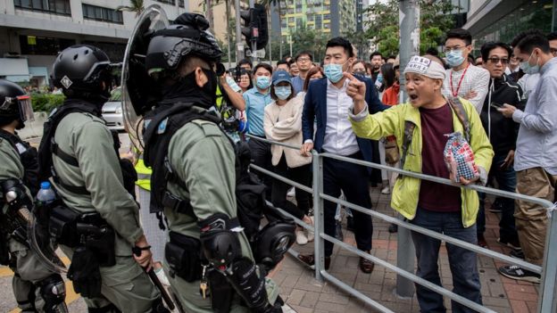 Riot police (L) arrive to disperse people gathering in support of pro-democracy protesters during a lunch break rally in the Kowloon Bay area in Hong Kong on November 26, 2019