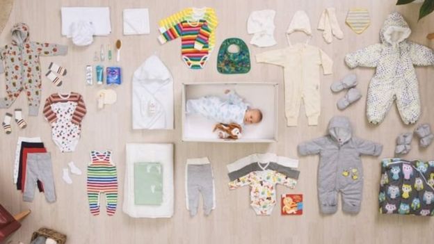 Bebê dentro da caixa de papelão, com seus produtos ao lado