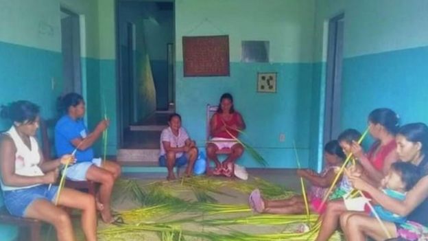 Mulheres indígenas se reunem para fazer artesanato