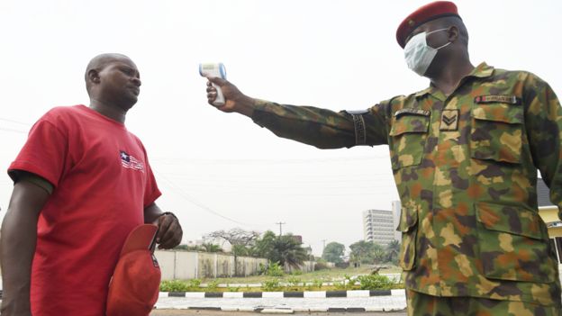 Un soldat pointe un thermomètre sur un homme à l'hôpital de référence de l'armée nigériane à Lagos, au Nigeria - vendredi 28 février 2020