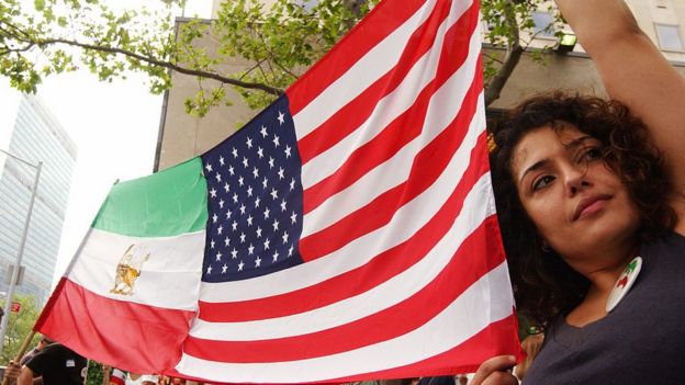 Mujer sosteniendo banderas de IrÃ¡n y Estados Unidos.