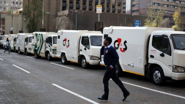 A cash-in-transit worker walks past armoured vehicles parked on the street during a nationwide protest following a spate of deadly heists this year, in Johannesburg, South Africa, June 12, 2018.
