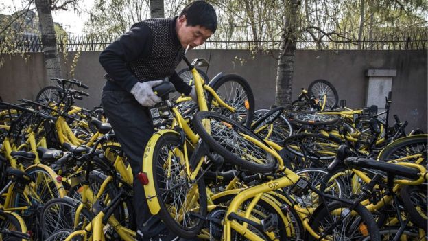 A man holds a broken bike from the Chinese bike sharing scheme