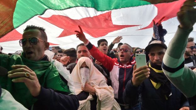 Algerians wave a flag during protests in Algiers