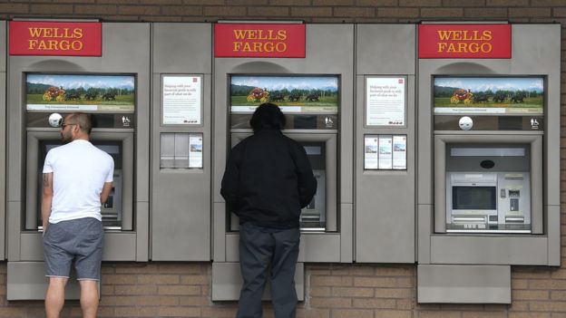 Dos personas usan los cajeros automáticos de Wells Fargo.