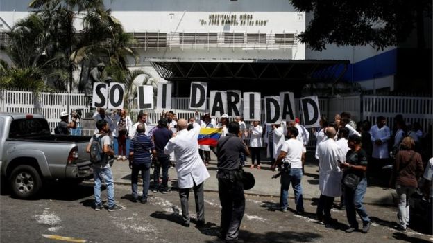 Venezuelans, including doctors, hold banners that read "Solidarity" as they gather outside a public children hospital during an ongoing blackout in Caracas, Venezuela March 10, 2019.