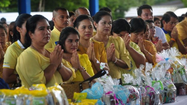 Well-wishers pray with offerings for Buddhist monks during a nationwide ceremony marking the birthday of the late Thai King Bhumibol Adulyadej in Thailand's southern province of Narathiwat on December 5, 2018.