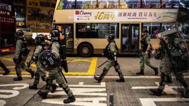 Riot police walk past a bus, Hong Kong, 5 October 2019