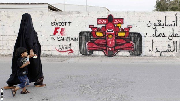 A woman and her child in front of anti-Formula One graffiti in the village of Barbar, Bahrain