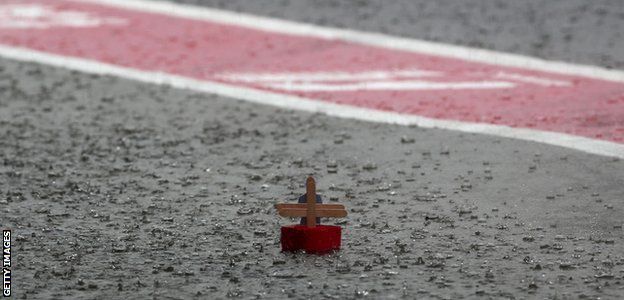A paper boat floats in the pit lane as heavy rain delays the second practice